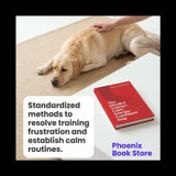 Dog lying on a mat with a person petting it, next to a book titled 'The Mindful Trainer' on a table.